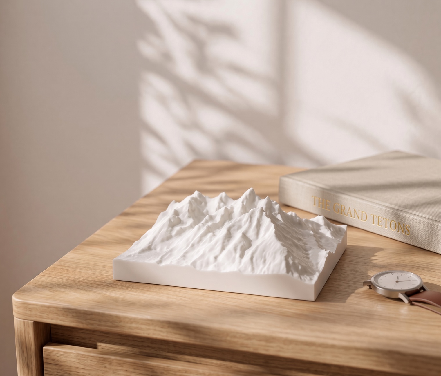 Grand Teton model on a desk with a book and watch